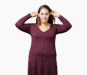 Obraz na płótnie Canvas Beautiful and attractive plus size young woman wearing a dress over isolated background Smiling pulling ears with fingers, funny gesture. Audition problem