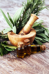 Fresh herbs from the garden and the different types of oils for massage and aromatherapy on table
