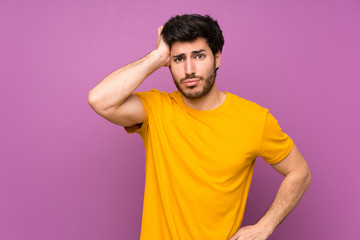 Handsome over isolated purple wall with an expression of frustration and not understanding