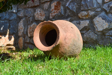 Decorative ancient Greek amphora lies in the garden in summer as a decoration. Fragment of landscape design