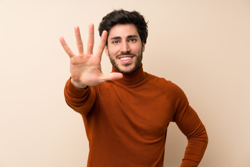 Handsome over isolated wall counting five with fingers