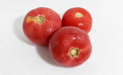 Red tomatoes with water drops on the white with reflection