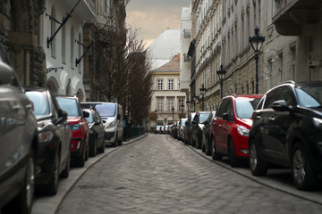 Obraz premium Cars parked in line on both sides of old city street 