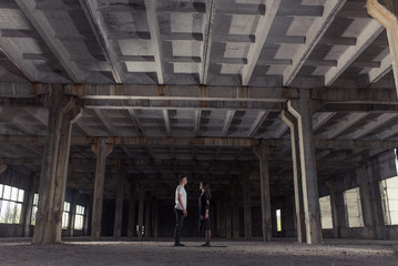 A young girl and boy perform acrobatic moves in the premises of an old factory, a warehouse, acro 