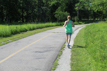 Woman running on the North Branch Trail in summer at Miami Woods in Morton Grove, Illinois