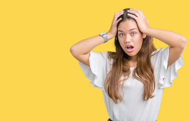 Young beautiful brunette business woman over isolated background Crazy and scared with hands on head, afraid and surprised of shock with open mouth