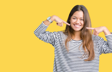 Young beautiful brunette woman wearing stripes sweater over isolated background smiling confident showing and pointing with fingers teeth and mouth. Health concept.