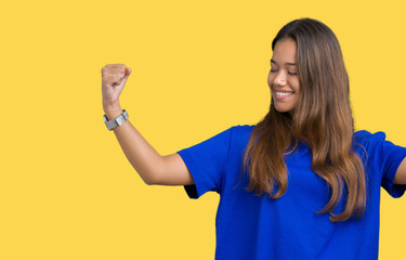 Young beautiful brunette woman wearing blue t-shirt over isolated background showing arms muscles smiling proud. Fitness concept.