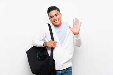 Sport man over isolated white wall saluting with hand with happy expression
