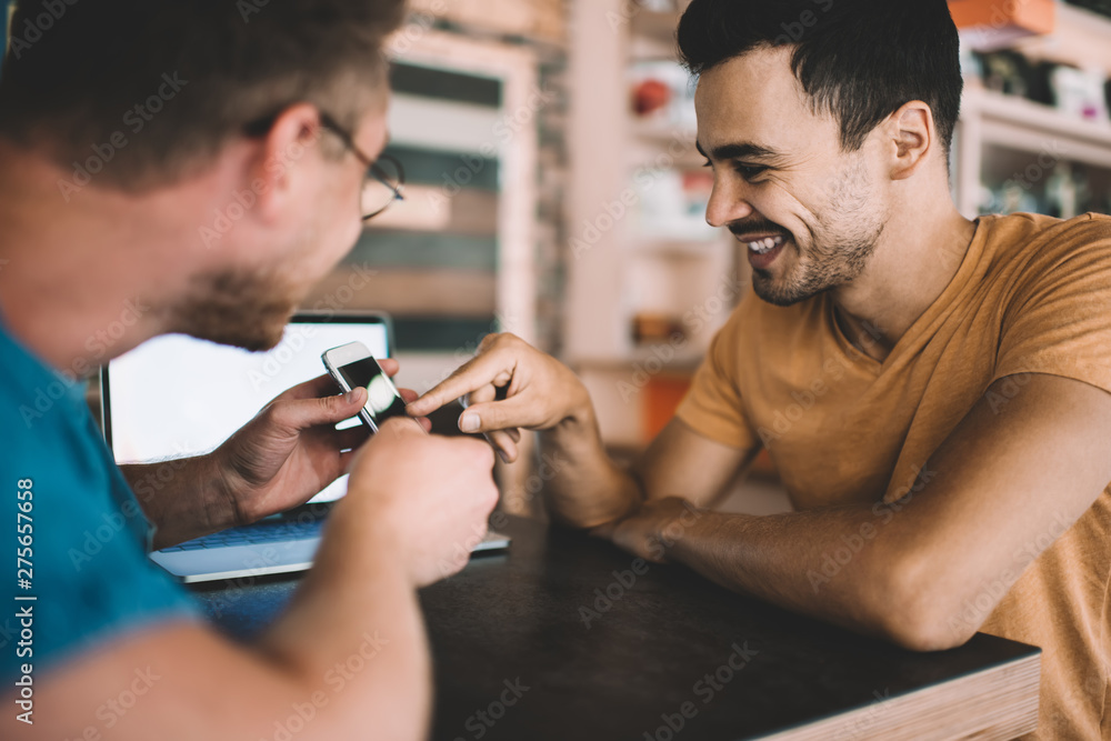 Aufkleber happy male bloggers discussing notification for application on smartphone gadget sitting at table an
