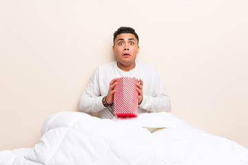 Young man in bed with popcorns