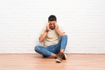 Young man sitting on the floor unhappy and frustrated with something. Negative facial expression