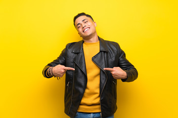 Young man over isolated yellow background proud and self-satisfied