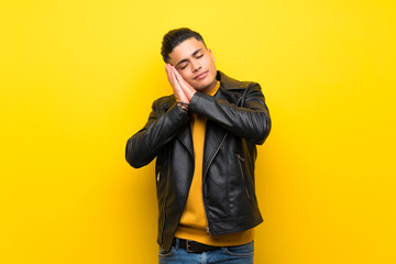 Young man over isolated yellow background making sleep gesture in dorable expression