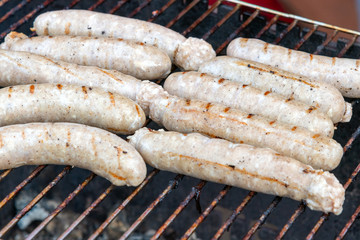 Cooking of sausages on barbeque.