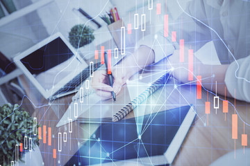 Financial graph displayed on woman's hand taking notes background. Concept of research. Double exposure