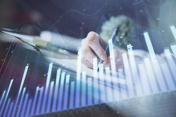 Financial forex graph displayed on hands taking notes background. Concept of research. Multi exposure