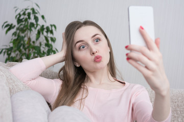 Selfie of attractive girl, pouting lips, sitting at home on the couch, close up