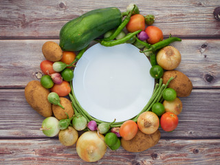 Many fresh vegetables are placed on a wooden table.