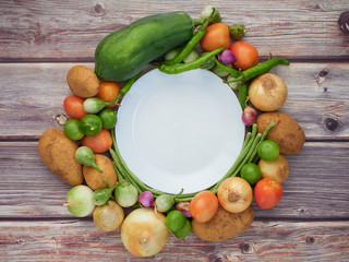 Many fresh vegetables are placed on a wooden table.