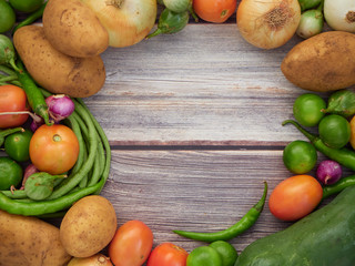 Many fresh vegetables are placed on a wooden table.