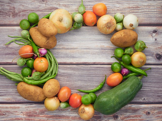 Many fresh vegetables are placed on a wooden table.