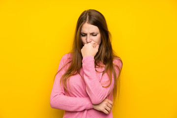 Young woman with long hair over isolated yellow wall having doubts