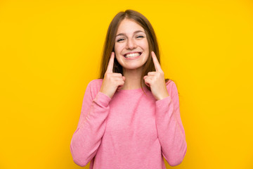 Young woman with long hair over isolated yellow wall smiling with a happy and pleasant expression
