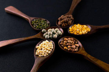 collection set of urad dal, beans, green peas, lentils, rice in wooden spoons.