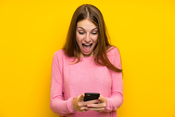 Fototapeta premium Young woman with long hair over isolated yellow wall surprised and sending a message