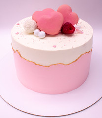 Delicate pink cake decorated with hearts and berries. On a white background.