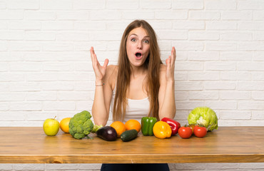 Young woman with many vegetables with surprise facial expression