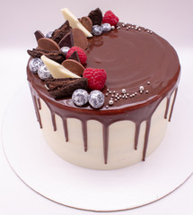 Cake on a white background decorated with chocolate drops and berries. Silver-covered blueberries.