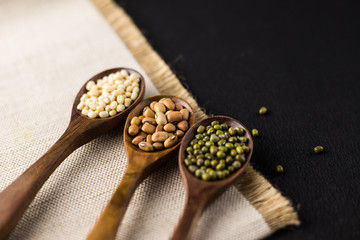 collection set of urad dal, beans, green peas, lentils, rice in wooden spoons.
