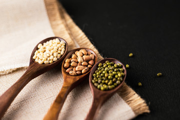 collection set of urad dal, beans, green peas, lentils, rice in wooden spoons.