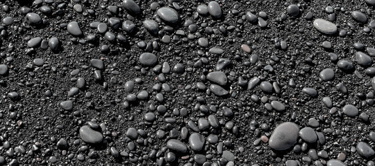 Wet black pebbles from black sand beach of Reynisfjara beach in Iceland
