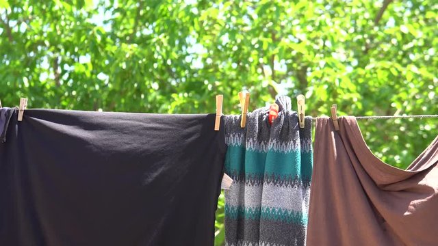 Clean Washed Clothes hanged on wire with clothes peg and blurred Spring Nature background in village.