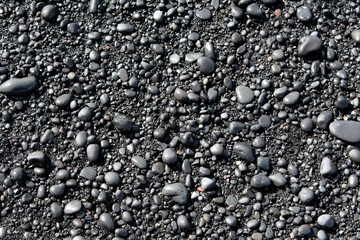 Wet black pebbles from black sand beach of Reynisfjara beach in Iceland