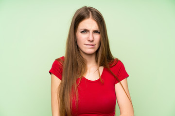 Young woman with long hair over isolated green wall having doubts and with confuse face expression