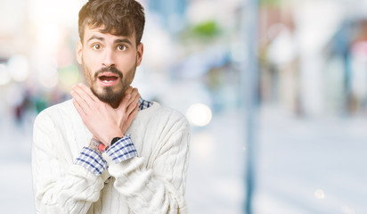 Young handsome man wearing winter sweater over isolated background shouting and suffocate because painful strangle. Health problem. Asphyxiate and suicide concept.