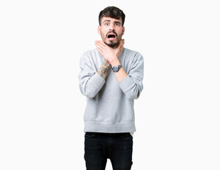 Young handsome man wearing sweatshirt over isolated background shouting and suffocate because painful strangle. Health problem. Asphyxiate and suicide concept.