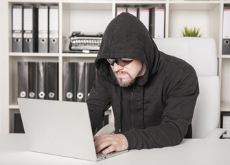 Man hacker using laptop in office