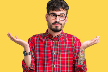Young handsome man wearing glasses over isolated background clueless and confused expression with...