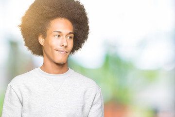 Young african american man with afro hair wearing sporty sweatshirt looking away to side with smile on face, natural expression. Laughing confident.