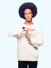 Young african american man with afro hair wearing glasses Doing time out gesture with hands,...