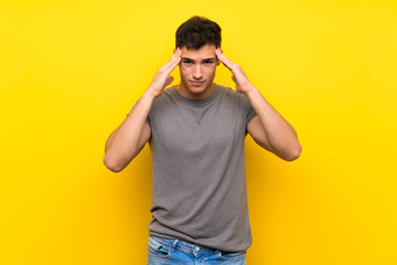 Handsome man over isolated yellow wall with headache