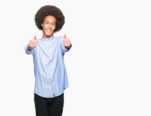 Young african american man with afro hair approving doing positive gesture with hand, thumbs up smiling and happy for success. Looking at the camera, winner gesture.