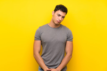 Handsome man over isolated yellow wall with sad and depressed expression