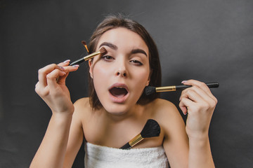 Fototapeta premium Close up portrait of gorgeous caucasian girl in white towel holds makeup brushes.
