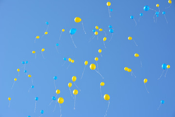 Many blue and yellow balloons flying high in the sky. Blue sky with lots balloons.